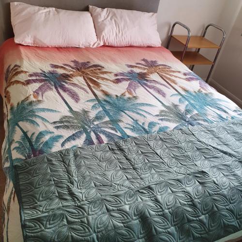a bed with a blanket with palm trees on it at 2-bedroom Back Hilton Area apartment - Ground Floor, Aberdeen city center in Aberdeen