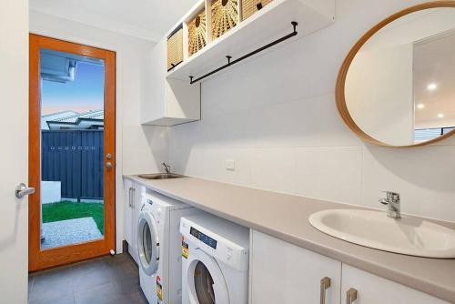 y baño con lavabo y lavadora. en Linear Park Living - Brand New 4 Bed Family Home, en Thebarton
