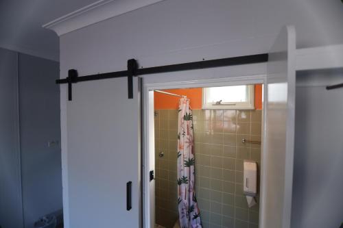 puerta del baño con cortina de ducha en Motel Melrose, en Mittagong