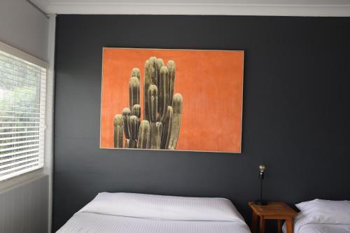 a bedroom with two beds and a painting of a cactus at Motel Melrose in Mittagong