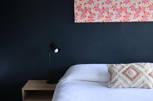 a blue bedroom with a bed with a pillow and a lamp at Motel Melrose in Mittagong