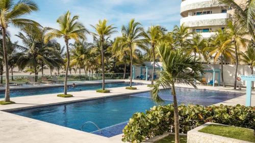 einem Pool mit Palmen vor einem Gebäude in der Unterkunft apartamento 1 alcoba morros 922 rnt 132107 in Cartagena de Indias