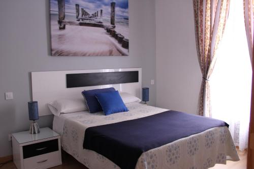 a bedroom with a bed with blue pillows and a pier at Casa de Huéspedes Galaica in Madrid