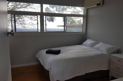 a bedroom with a white bed with two windows at Family Home Prestigious Suburb Panoramic Views in Glenunga