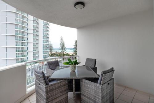 a dining room with a table and chairs on a balcony at Kirra Beach Apartments in Gold Coast