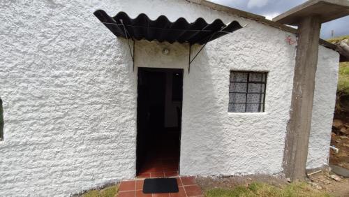 a door to a white building with a black roof at Cabañas Casa Campo Guatavita in Guatavita