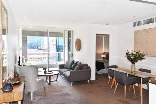 a living room with a couch and a table at Luxury Overlooking Hindmarsh Sq with Pool & Gym in Adelaide
