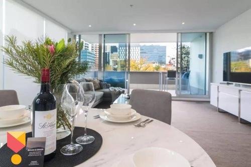 a bottle of wine on a table in a living room at Marble CBD Luxury 2 Bedroom Apt Pool & Parking in Adelaide