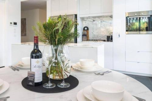 a table with a bottle of wine and two glasses at Marble CBD Luxury 2 Bedroom Apt Pool & Parking in Adelaide