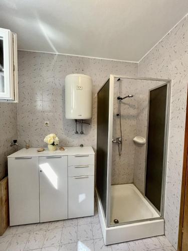a white bathroom with a shower and a sink at Apartments Veli Rat in Veli Rat