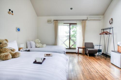 a hotel room with two beds with teddy bears on them at Adagio Hokkaido in Biei