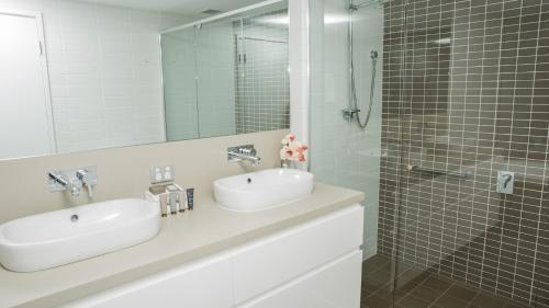 uma casa de banho com 2 lavatórios e um chuveiro em Bridgepoint 103 em Mandurah