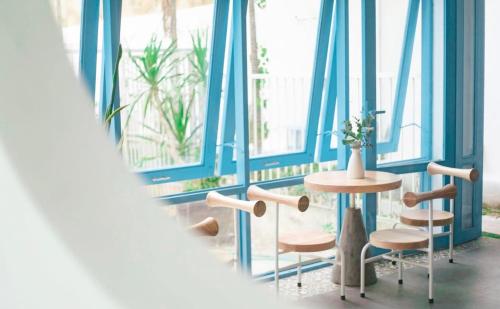 a table and chairs in a room with blue walls and windows at Tò Vò Hostel Huế in Hue