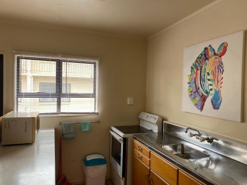 a kitchen with a sink and a painting of a horse on the wall at Wayfarer Motel in Kaitaia