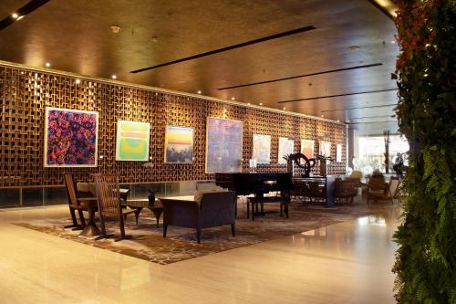 a lobby with a grand piano and tables and chairs at ARTOTEL Suites Bianti Yogyakarta, CHSE Certified in Yogyakarta