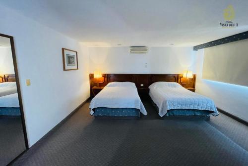 una camera d'albergo con due letti e uno specchio di Hotel Posada Vista Bella a Morelia