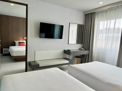 パトンビーチにあるCentro One Patongのベッド2台と鏡が備わるホテルルームです。
