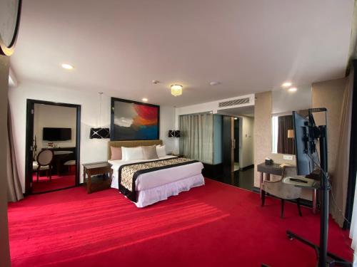 Habitación de hotel con cama y alfombra roja en Amaroossa Cosmo Jakarta, en Yakarta