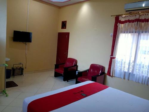 um quarto com uma cama e 2 cadeiras e uma televisão em RedDoorz @ Puncak Tahura Hotel Bengkulu Tengah em Bengkulu