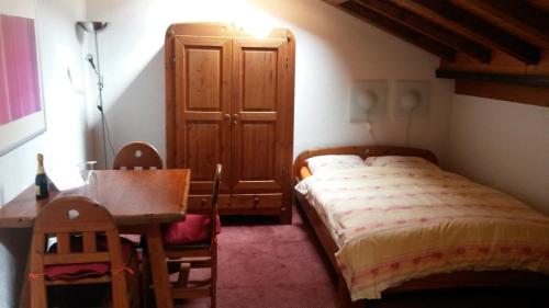 Schlafzimmer mit einem Bett, einem Schreibtisch und einem Tisch in der Unterkunft Haus Arbgrat in Zermatt
