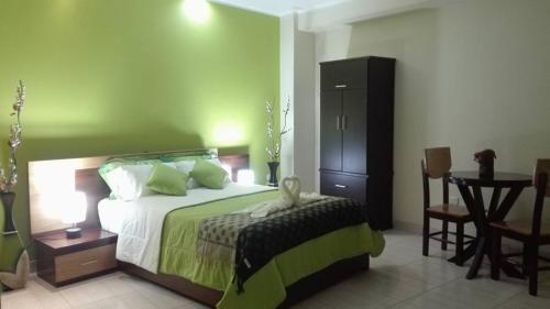 a bedroom with a bed with a green wall at Hostal "Vista del Valle" in La Merced