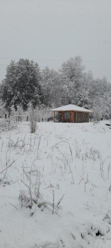 een veld bedekt met sneeuw met een gebouw op de achtergrond bij José María in Melipeuco