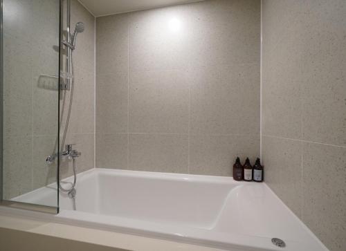 a bathroom with a bath tub with a shower at Ocean city hotel in Busan
