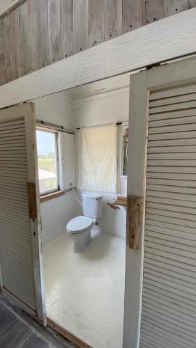 a small bathroom with a toilet and a window at The 99 Cottage (บ้านทุ่งบางปลาม้า) in Suphan Buri