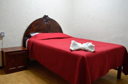 - une chambre dotée d'un lit rouge avec un couvre-lit rouge et un oriel blanc dans l'établissement Hotel Casa Genesis, à Oaxaca