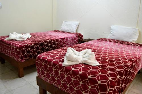 - 2 lits avec des draps rouges et des arcs blancs dans l'établissement Hotel Casa Genesis, à Oaxaca