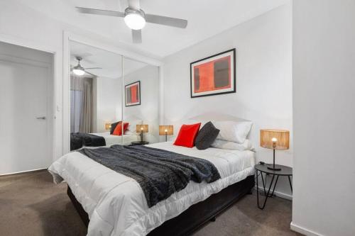 a white bedroom with two beds and two lamps at Astral Apartments. Spacious 2 bed, 2 bath apartment in a great location. in Melbourne
