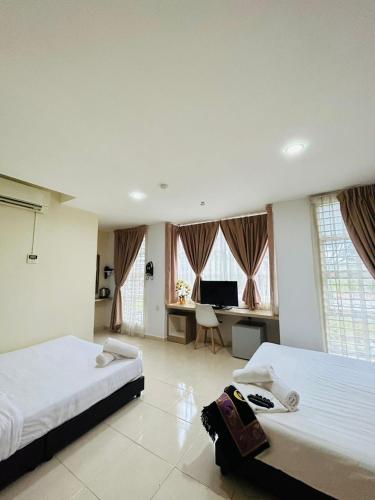 a bedroom with two beds and a desk in it at Noor Hotel Kangar in Kangar