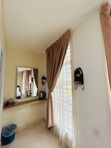 a window with a curtain and a mirror in a room at Noor Hotel Kangar in Kangar