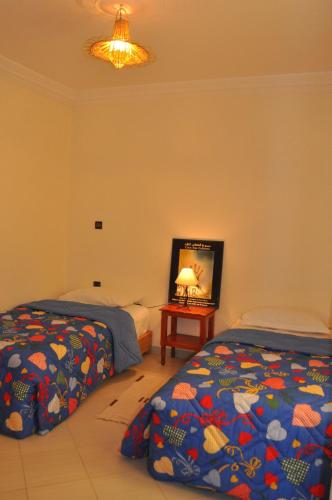 a bedroom with two beds and a television in it at Résidence La Galiote in Essaouira