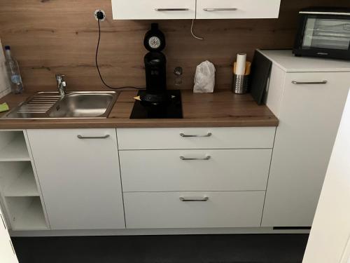 een keuken met witte kasten en een wastafel bij Gemütliches 1 Zimmer Appartement in Langelsheim