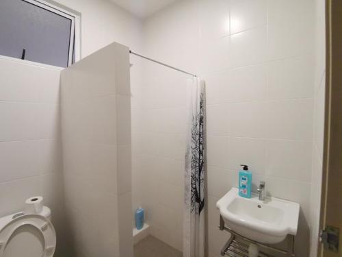a white bathroom with a toilet and a sink at Urban ONE Homestay 8pax 3Rooms in Kuching