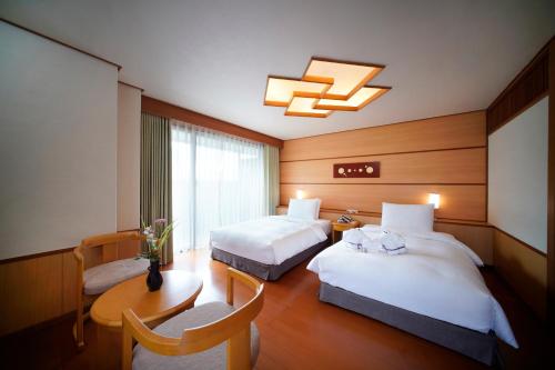 台北的住宿－北投日勝生加賀屋國際溫泉飯店，酒店客房设有两张床和一张桌子。