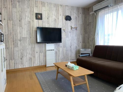 a living room with a couch and a tv on a wall at Creative　apartment in Kita-sanjō