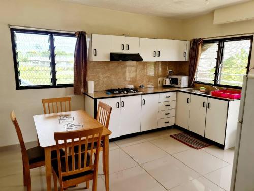 a kitchen with white cabinets and a table and chairs at Masters 2 Bedroom Apartment Westfield in Nadi