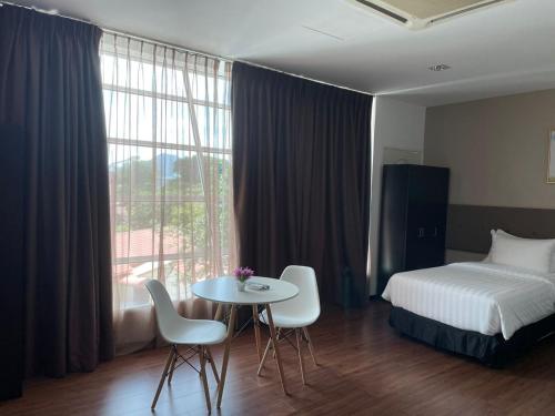 a hotel room with a bed and a table and chairs at King's Lane Ipoh in Ipoh