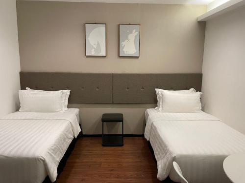 a room with two beds and two pictures on the wall at King's Lane Ipoh in Ipoh