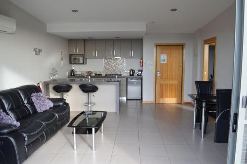 a living room with a black couch and a kitchen at Rocky Cape Retreat in Rocky Cape