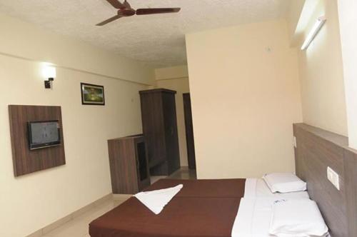 a bedroom with a bed and a ceiling fan at Hotel Shoven in Dāvangere