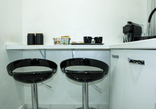 two black bar stools in front of a kitchen counter at Suite Élite in Catania