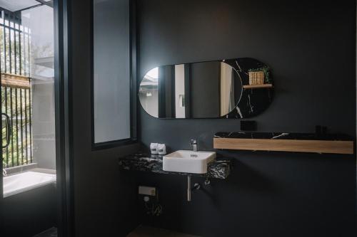 a black bathroom with a sink and a mirror at INN BLOG HOTEL Pakbara in Satun
