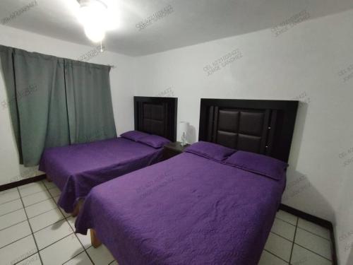 two beds in a room with purple sheets at Condominio 303 Loma Bonita, enfrente de la alberca! in San Carlos