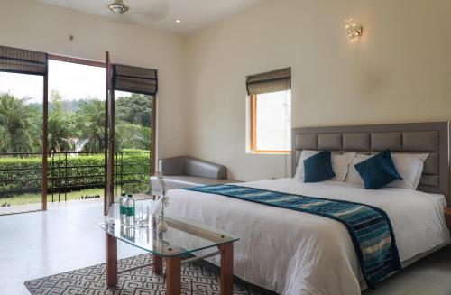 a bedroom with a bed and a glass table at Corbett Panorama Resort in Rāmnagar