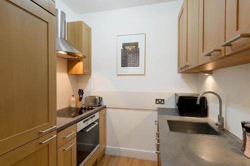 a small kitchen with a sink and a stove at Notting Hill Apartment Portobello Road, Hyde Park & Tube in London