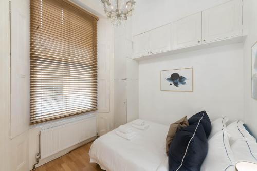 Un dormitorio con una cama y una ventana con una lámpara de araña. en Notting Hill Apartment, en Londres