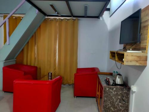 a living room with two red chairs and a tv at Mountain view stay in Auli in Joshīmath